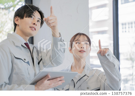 A man and a woman in work clothes having a meeting A man and a woman in work clothes having a meeting 138757376