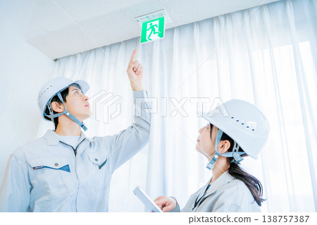 Men and women in work clothes inspecting fire safety equipment. 138757387