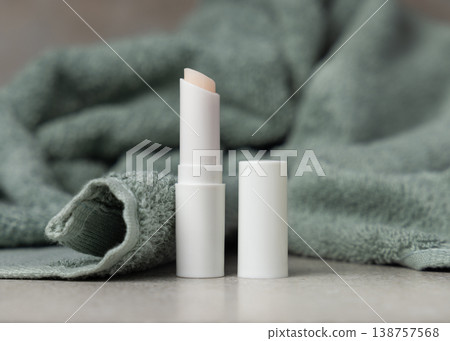 White opened lip balm stick mockup with a lid near light green bath towel, unbranded packaging 138757568
