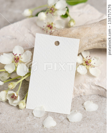 Blank vertical gift tag mockup with white spring flowers and driftwood on light stone, product tag 138757576