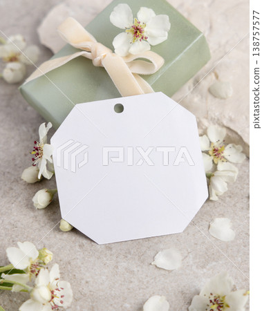 Blank gift tag mockup with white spring flowers and driftwood on light stone, label design 138757577