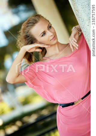 Elegant woman in pink dress posing outdoors gracefully 138757595