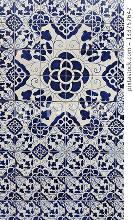 Decorative ceramic tile pattern featuring intricate blue and white floral designs arranged symmetrically on a wall, showcasing traditional craftsmanship and artistry Decorative ceramic tile pattern featuring intricate blue and white floral designs arranged symmetrically on a wall, showcasing traditional craftsmanship and artistry 138757642