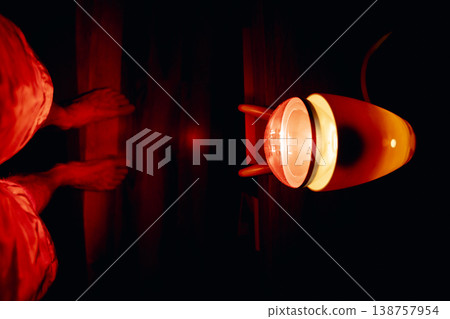 A red infrared lamp for medical therapy that emits intense heat in a dark environment and infrared light with a golden orange glow. A red infrared lamp for medical therapy that emits intense heat in a dark environment and infrared light with a golden orange glow. 138757954