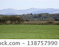 Tractor working on rural farmland with mountains in background 138757990