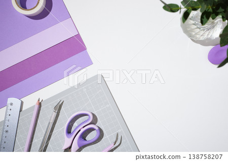 Top view of purple paper craft supplies on white background. Cutting mat, scissors, craft knife, ruler, and tape. Copyspace 138758207
