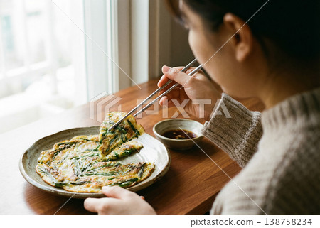 Person Eating Korean Chive Pancake with Chopsticks Close View Person Eating Korean Chive Pancake with Chopsticks Close View 138758234