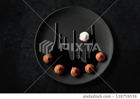 Chocolate truffles on a black plate. Chocolate truffles on a black plate. 138759338