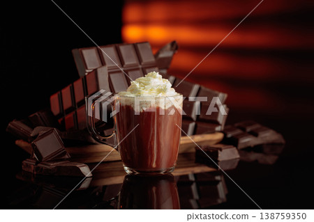 A mug of hot chocolate with whipped cream against broken bitter chocolate bars. 138759350