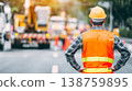 Construction worker manages roadwork site from back view with safety gear and equipment nearby 138759895