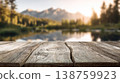 Rustic wooden tabletop with mountain lake landscape and sunrise light in the background 138759923