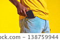 Person slips smartphone into front pocket of light blue jeans and a mustard t-shirt 138759944