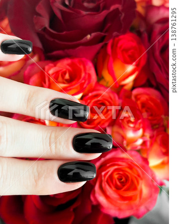 Demonstration of hand with black manicure on background of bunch with red and orange roses. Fingers slightly curled, polished nails. Contrast between dark nails and colorful roses, moment of beauty Demonstration of hand with black manicure on background of bunch with red and orange roses. Fingers slightly curled, polished nails. Contrast between dark nails and colorful roses, moment of beauty 138761295