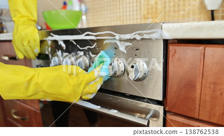 Hands clean a stove in a kitchen with soap and water during daytime activities Hands clean a stove in a kitchen with soap and water during daytime activities 138762538