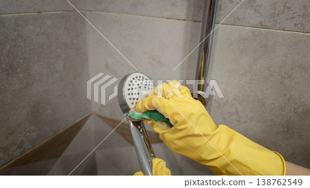 Cleaning a shower drain with a scrubber and yellow gloves in a tiled bathroom Cleaning a shower drain with a scrubber and yellow gloves in a tiled bathroom 138762549