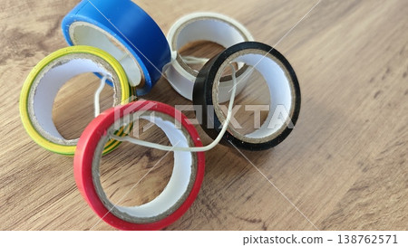 Different rolls of tape sit on a wooden surface in a casual arrangement Different rolls of tape sit on a wooden surface in a casual arrangement 138762571