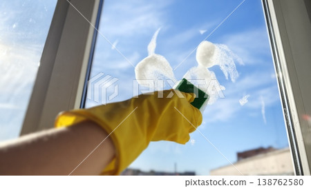 Cleaning a window with a sponge and soap on a clear sunny day Cleaning a window with a sponge and soap on a clear sunny day 138762580