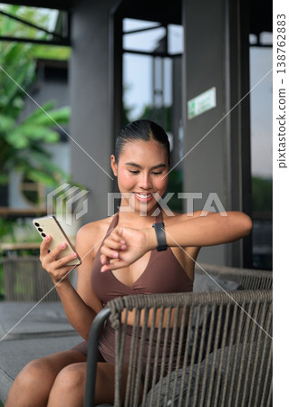 Young Thai Woman Syncing Fitness Data After Workout Gym Training Done Concept Young Thai Woman Syncing Fitness Data After Workout Gym Training Done Concept 138762883