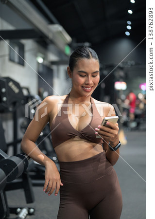 Smiling Thai Fitness Influencer Reviewing Stats on Smartphone Gym Training Done Concept Smiling Thai Fitness Influencer Reviewing Stats on Smartphone Gym Training Done Concept 138762893