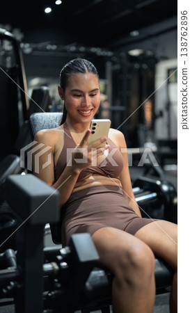 Thai Fitness Influencer Checking App on Leg Extension Machine Gym Training Done Concept 138762896