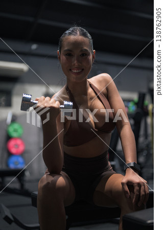 Smiling Thai Fitness Influencer Doing Bicep Curls with Dumbbell Modern Strength Training Concept 138762905