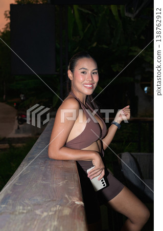 Happy Thai Fitness Influencer Posing at Twilight Outdoor Balcony Healthy Lifestyle Concept Happy Thai Fitness Influencer Posing at Twilight Outdoor Balcony Healthy Lifestyle Concept 138762912