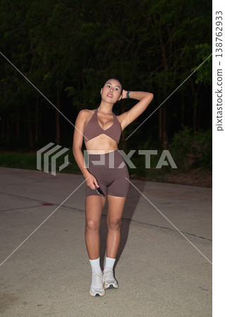 Athletic Thai Woman in Brown Halter Set Posing at Night Modern Outdoor Fitness Concept 138762933
