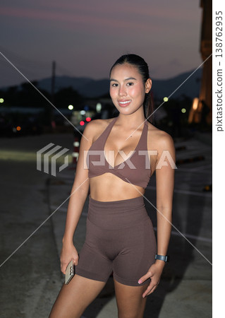 Smiling Thai Fitness Influencer in Brown Halter Gym Set Modern Outdoor Wellness Concept Smiling Thai Fitness Influencer in Brown Halter Gym Set Modern Outdoor Wellness Concept 138762935
