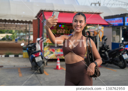 Thai Fitness Influencer Taking Selfie in Brown Activewear at Tropical Market Modern Digital Lifestyle Concept Thai Fitness Influencer Taking Selfie in Brown Activewear at Tropical Market Modern Digital Lifestyle Concept 138762950