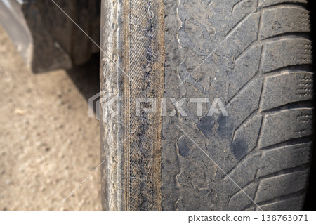 A close-up view of a car wheel shows significant damage and wear. The cracked tire serves as a reminder to check vehicle safety regularly 138763071