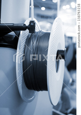 Spool of plastic wire for 3D printing. Spool with plastic close-up. Component for 3d printing. Printing accessories. Concept modern 3D printing technology. Additive modern progressive FDM technologies Spool of plastic wire for 3D printing. Spool with plastic close-up. Component for 3d printing. Printing accessories. Concept modern 3D printing technology. Additive modern progressive FDM technologies 138763158