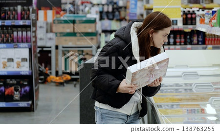 Woman shopping for groceries, choosing frozen food in brightly lit supermarket Woman shopping for groceries, choosing frozen food in brightly lit supermarket 138763255