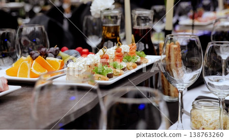 Elegant canapes featuring salmon, orange slices, grapes, figs, strawberries arranged on wooden serving board for upscale event dining Elegant canapes featuring salmon, orange slices, grapes, figs, strawberries arranged on wooden serving board for upscale event dining 138763260