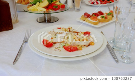 Grilled chicken caesar salad featuring crisp romaine, ripe tomatoes, golden croutons, drizzled with creamy dressing on pristine white plate 138763287