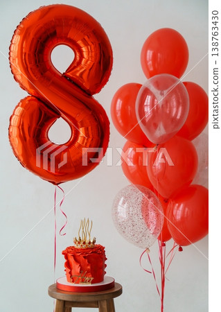 Metallic orange number eight balloon with red cake and confetti balloons on wooden stool for birthday celebration Metallic orange number eight balloon with red cake and confetti balloons on wooden stool for birthday celebration 138763430