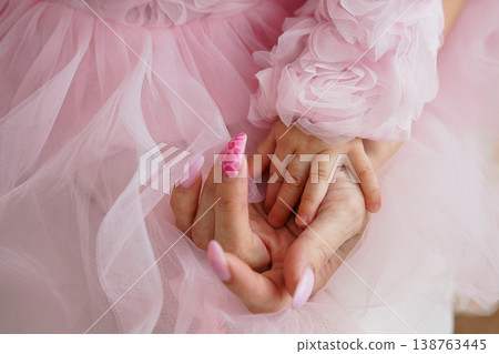 Mother and daughter hands holding together in soft pink tulle dress with heart nail art close up portrait Mother and daughter hands holding together in soft pink tulle dress with heart nail art close up portrait 138763445