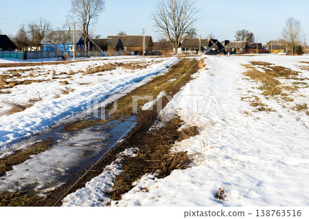 Country road scene. Rural path with puddles. Twisted trail amidst rain and thawing ground 138763516