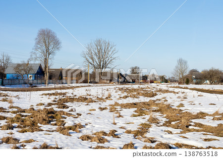 Frozen terrain opening to muddy patches and scattered dwellings beneath blue sky Frozen terrain opening to muddy patches and scattered dwellings beneath blue sky 138763518