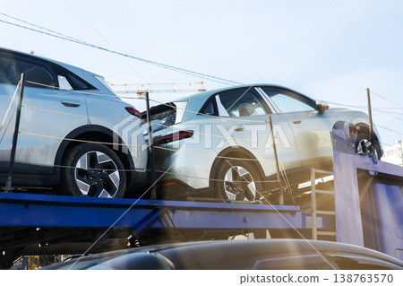 Shiny silver sports utility vehicles arranged on carrier truck in open freight yard 138763570