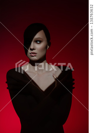 Elegant woman poses confidently against a bold red backdrop Elegant woman poses confidently against a bold red backdrop 138763632