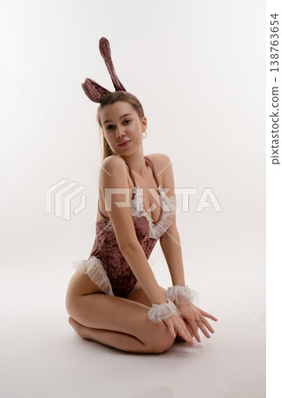 Woman in artistic pose wearing elegant costume with bunny ears and cuffs Woman in artistic pose wearing elegant costume with bunny ears and cuffs 138763654