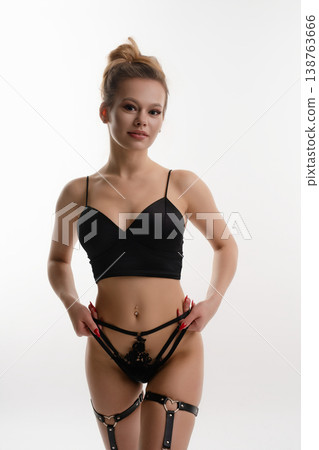 Woman poses confidently in black lingerie against a clean backdrop Woman poses confidently in black lingerie against a clean backdrop 138763666