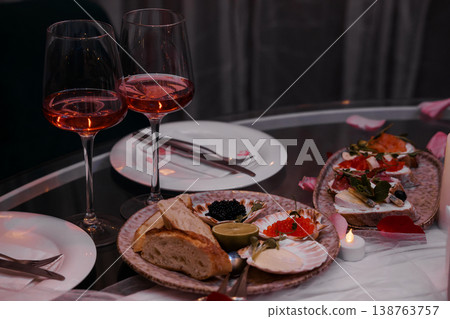 Romantic Dinner With Rose Wine And Seafood Caviar Canapes On Glass Table With Candlelight And Rose Petals Romantic Dinner With Rose Wine And Seafood Caviar Canapes On Glass Table With Candlelight And Rose Petals 138763757