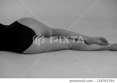Monochrome studio portrait of a woman's legs and hips in black lingerie reclining on a white surface Monochrome studio portrait of a woman's legs and hips in black lingerie reclining on a white surface 138763764