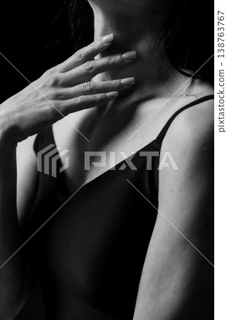 Black and white portrait of woman touching neck with manicured nails in dark studio lighting Black and white portrait of woman touching neck with manicured nails in dark studio lighting 138763767