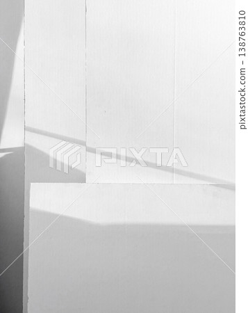 Bright light shines on white surface, shadows create distinct shapes and patterns. Varying layers with lines of light cutting across surface, simple beauty of light interacting with color and form 138763810