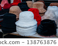 Detailed View Of City Market Vendor Organizing Variety Of Plush Winter Hats In Neutral Colors 138763876