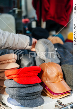 Stylish Headgear On Street Scene. Market Display Features Diverse Caps And Berets In Bold Hues Stylish Headgear On Street Scene. Market Display Features Diverse Caps And Berets In Bold Hues 138763877