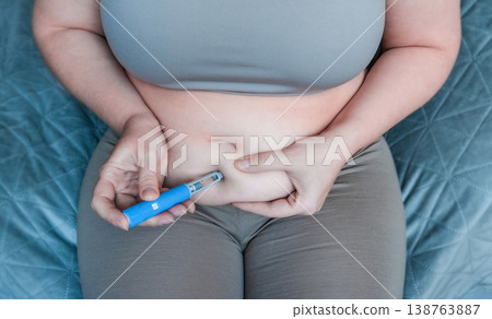 Woman injecting GLP-1 agonist into abdomen for weight loss Woman injecting GLP-1 agonist into abdomen for weight loss 138763887