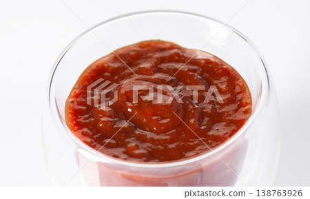 Fresh red tomato sauce with herbs in a clear glass bowl, isolated on a white background. Fresh red tomato sauce with herbs in a clear glass bowl, isolated on a white background. 138763926